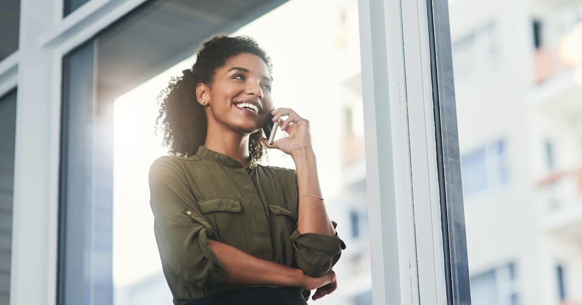 Asesora inmobiliaria sonriente hablando por teléfono, representando una actitud positiva y constante en su proceso de prospección.