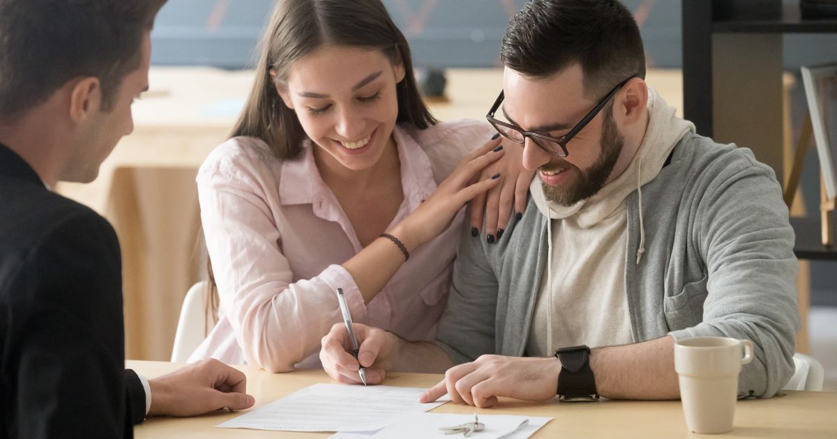 Pareja feliz firmando documento de la compra de una casa